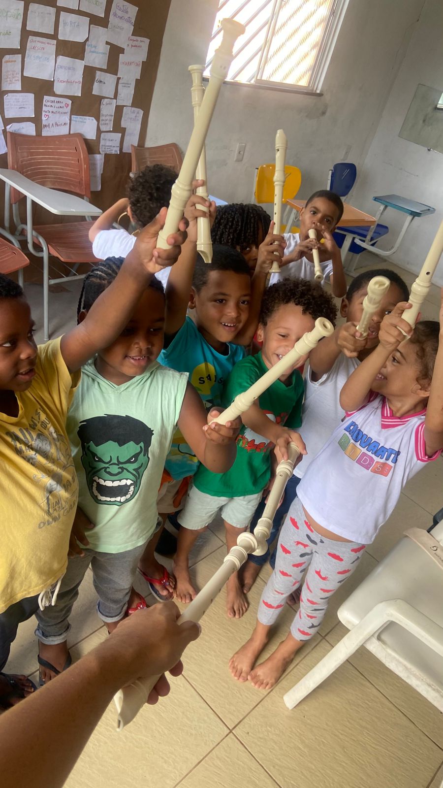 Crianças menores erguendo flautas animadas